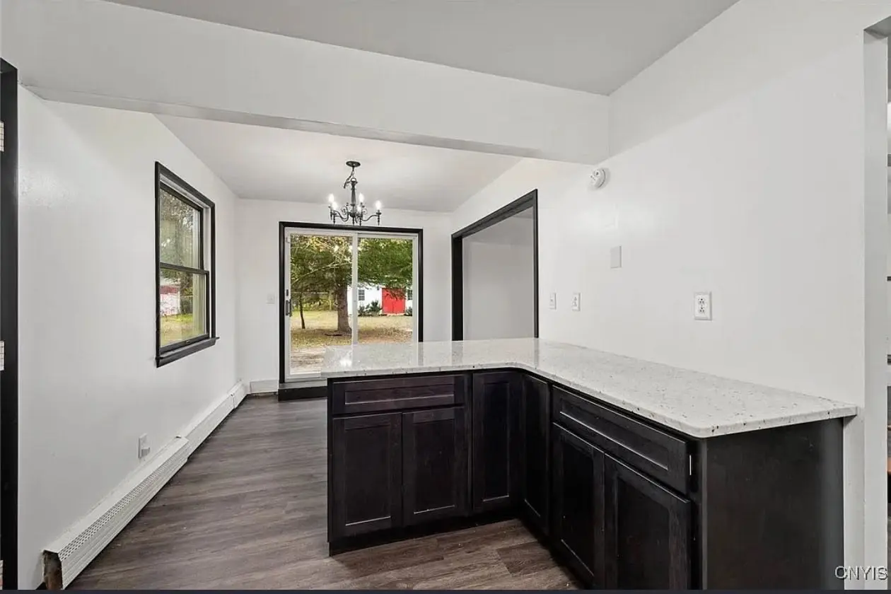 Open kitchen peninsula with stone countertop and dining area beyond