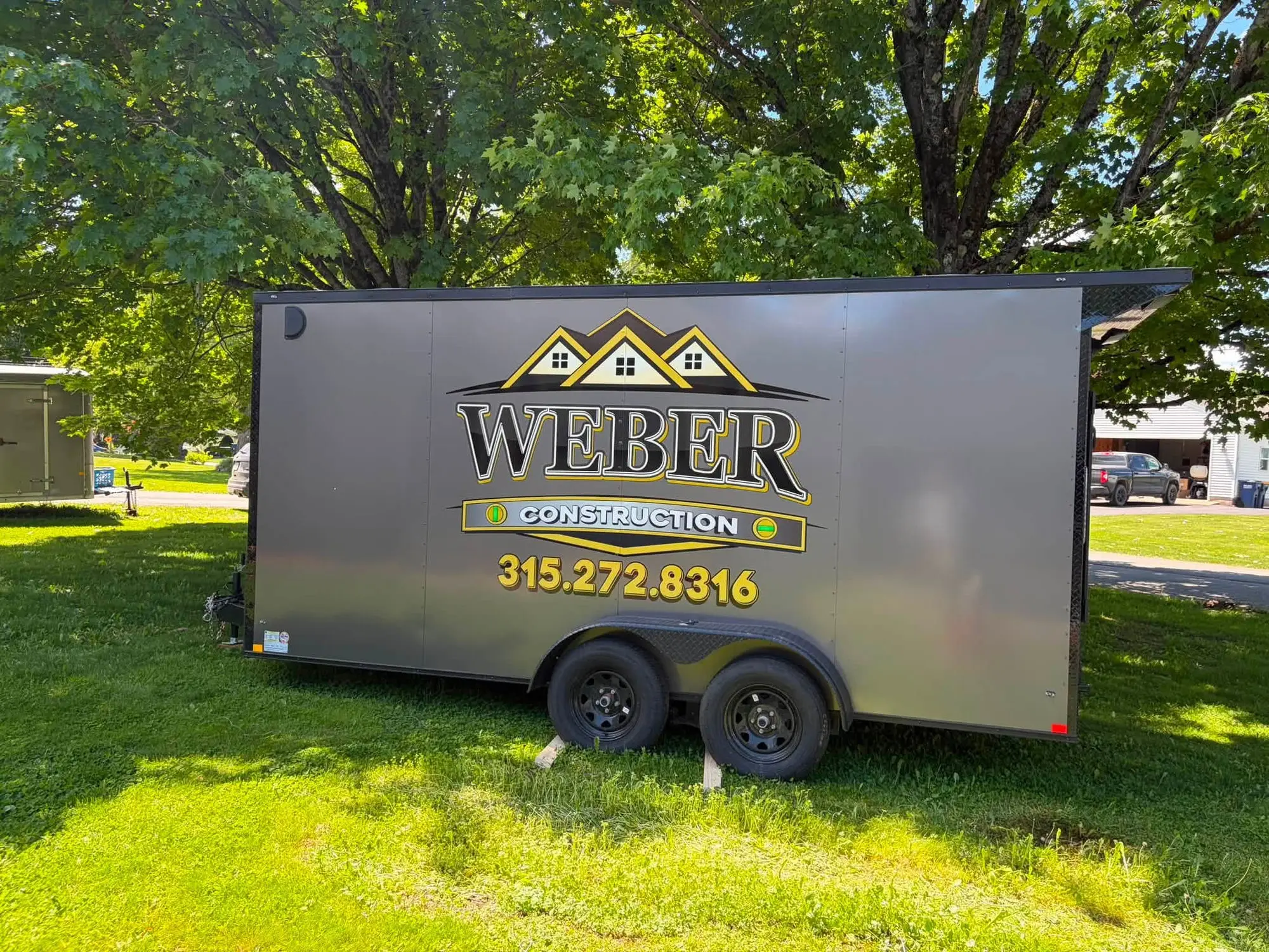 Weber Construction's branded enclosed work trailer parked at a job site